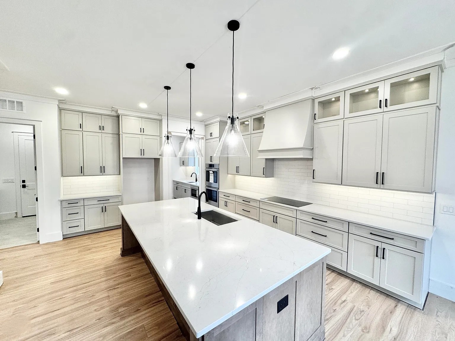 Custom kitchen with light gray cabinets, quartz island and glass pendant lighting