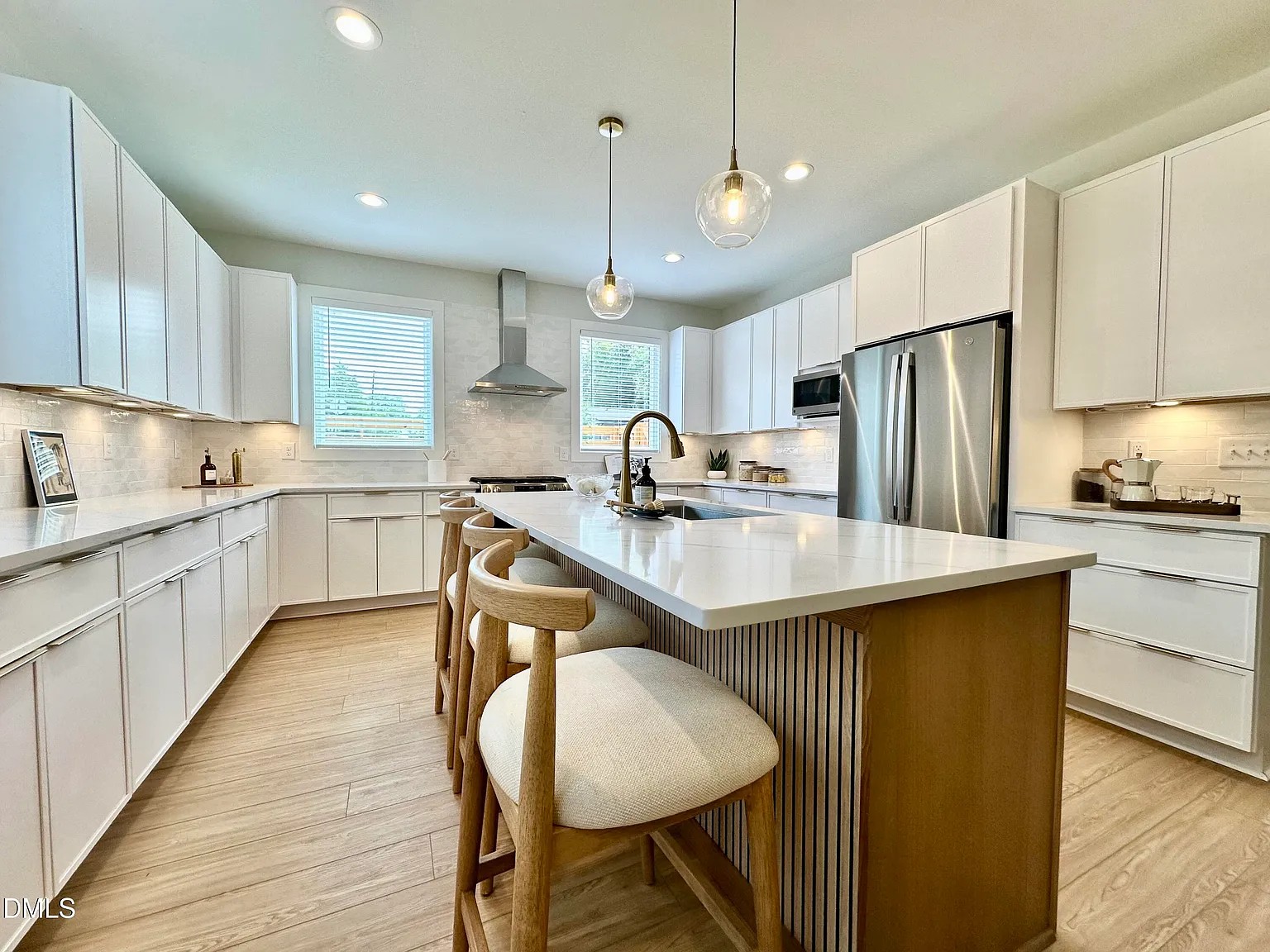 Bright modern kitchen with white cabinets, island seating, and pendant lighting by Badger Homes