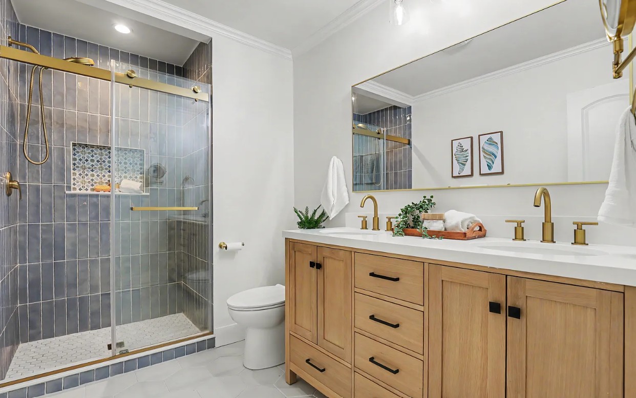 Bathroom remodel with blue vertical tile shower, gold fixtures and natural wood vanity