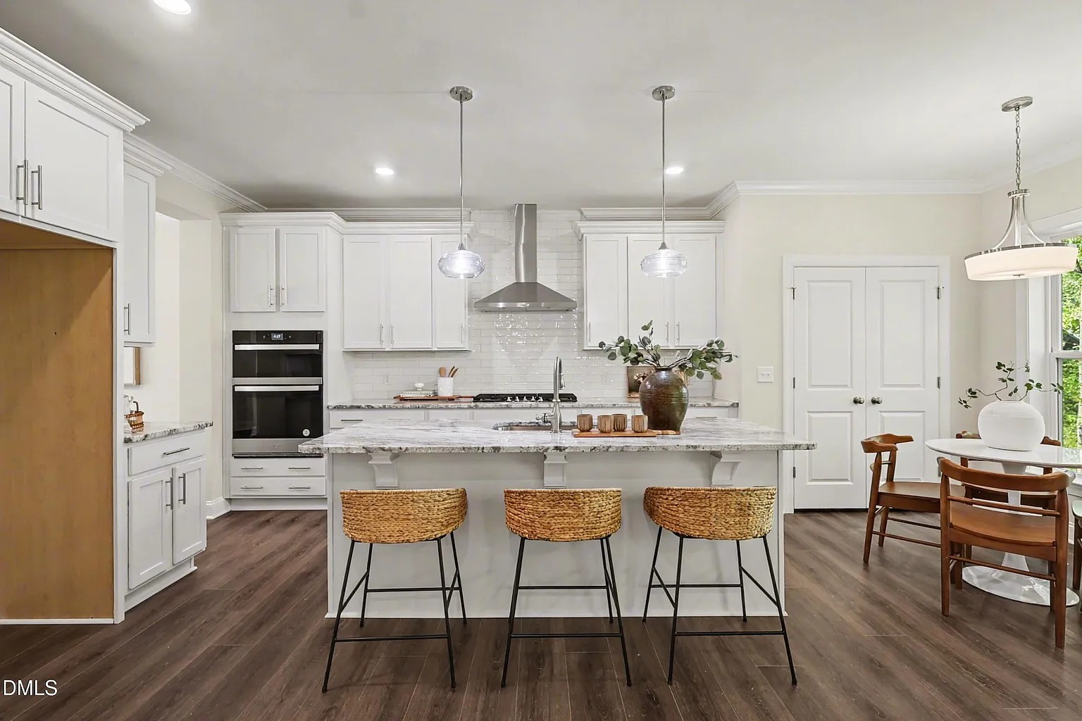 White kitchen remodel with granite island, woven barstools and stainless hood